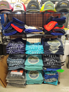 Hats and beanies, shirts on black wire rack for sale at Timberline Sports-N-Convenience