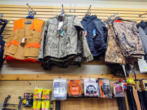 Hutning clothes, vests, and ear plugs on the wall for sale at Timberline Sports-N-Convenience